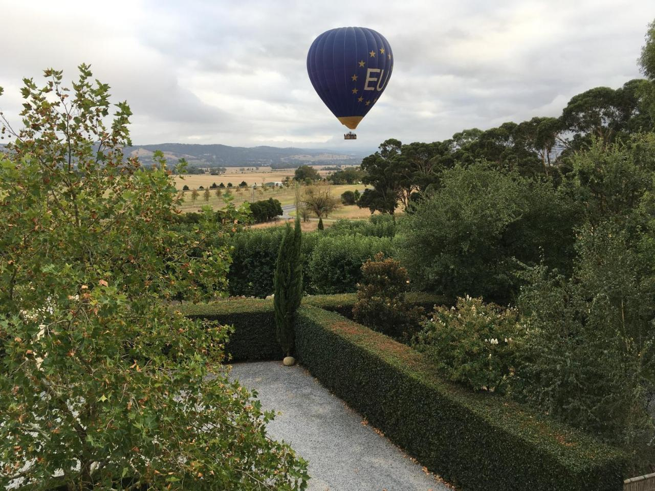 Hot air balloon drifting above the Villa Capra gardens and Yarra Valley