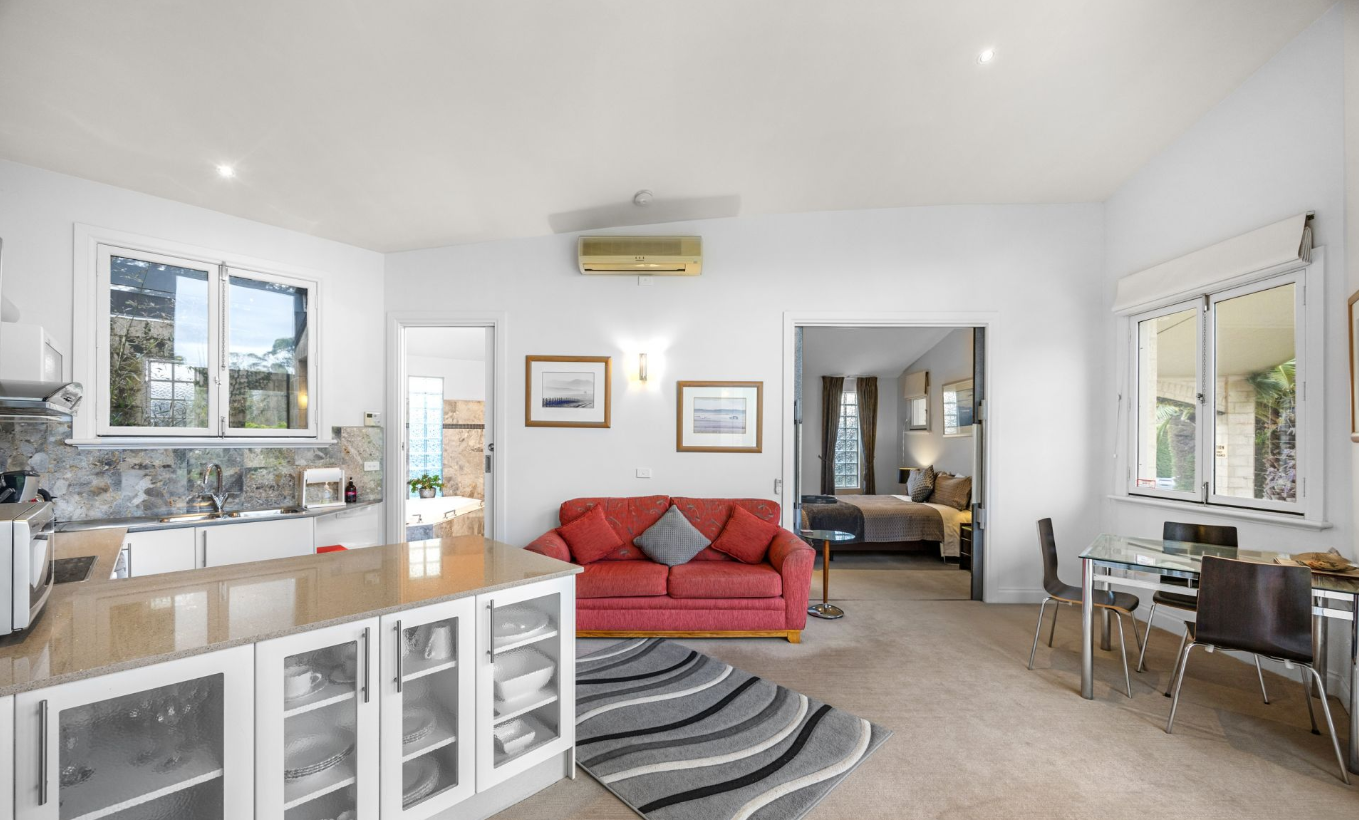 The Yarra Suite living area in cool grey tones with queen bed beyond